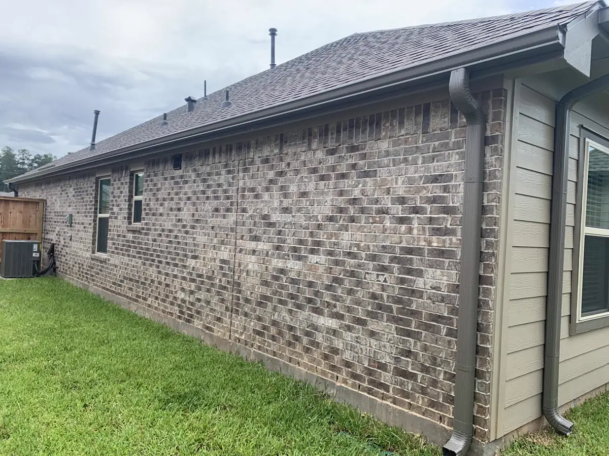 Brown seamless gutters and downspouts installed on a Conroe-area brick home