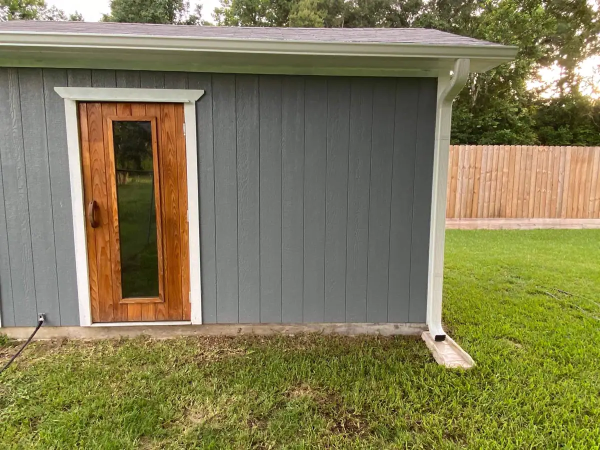 Seamless gutter and downspout installed on a gray detached building